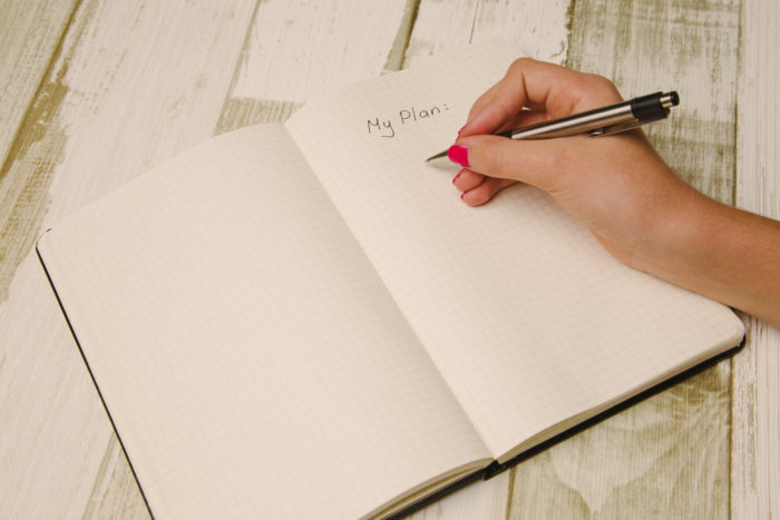 Female hand holding a pen and writing a plan in a planner